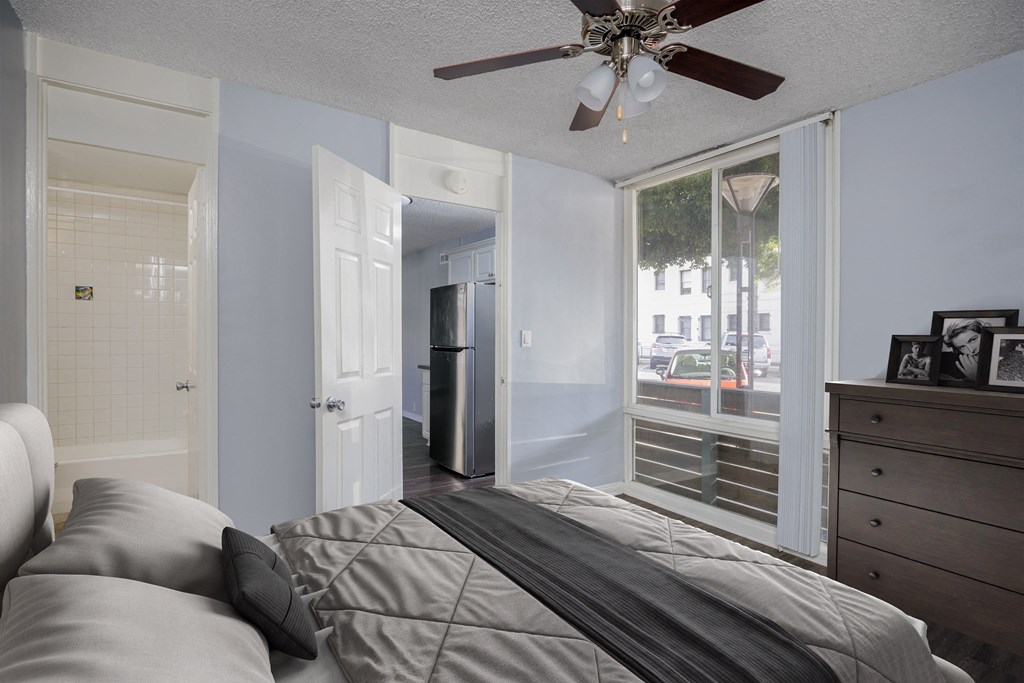 A bedroom with a bed, dresser, and a ceiling fan.