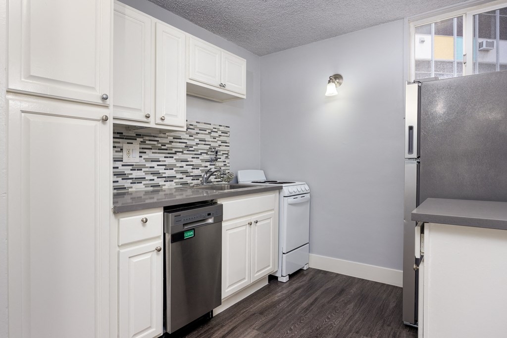 A kitchen with white cabinets and a black dishwasher.