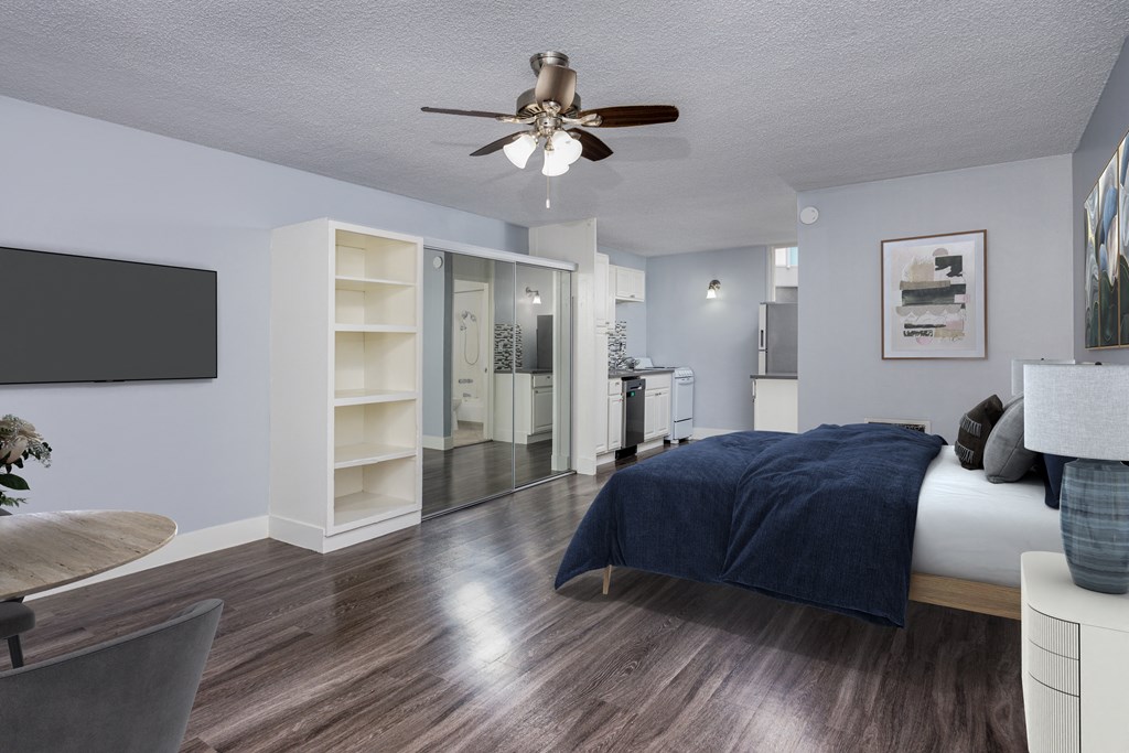 A bedroom with a bed, a chair, and a ceiling fan.