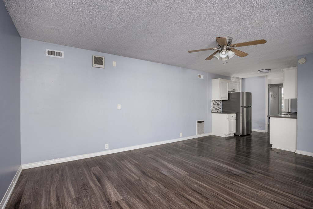 A room with a ceiling fan and a refrigerator.