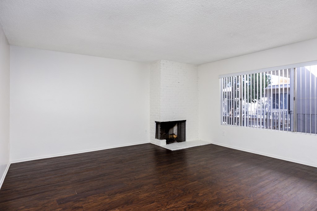 an empty living room with wood floors and a fireplace