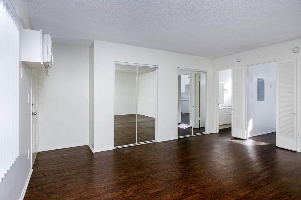 an empty living room with a hard wood floor and a mirrored closet