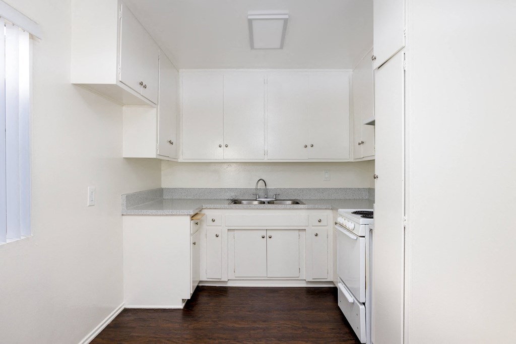 a kitchen with white cabinets and white appliances and a wood floor