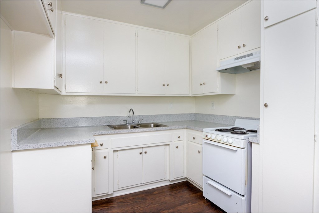 a kitchen with white cabinets and white appliances and a sink