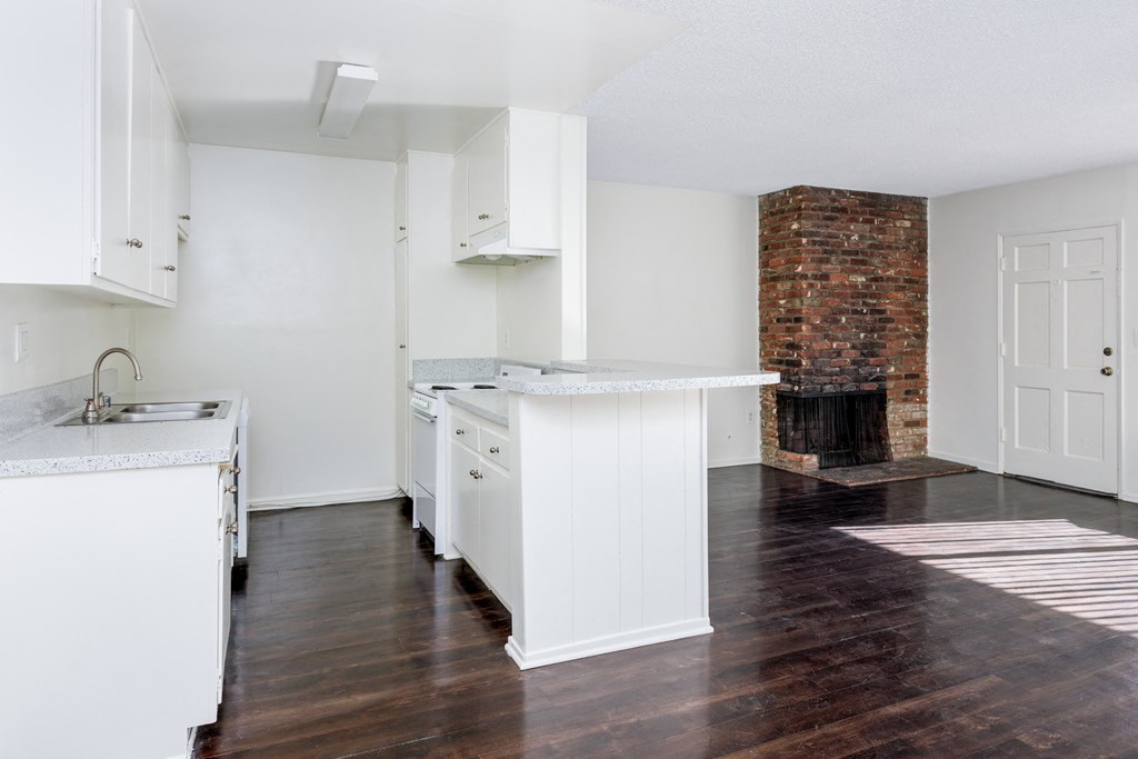 an empty kitchen with white cabinets and a fireplace