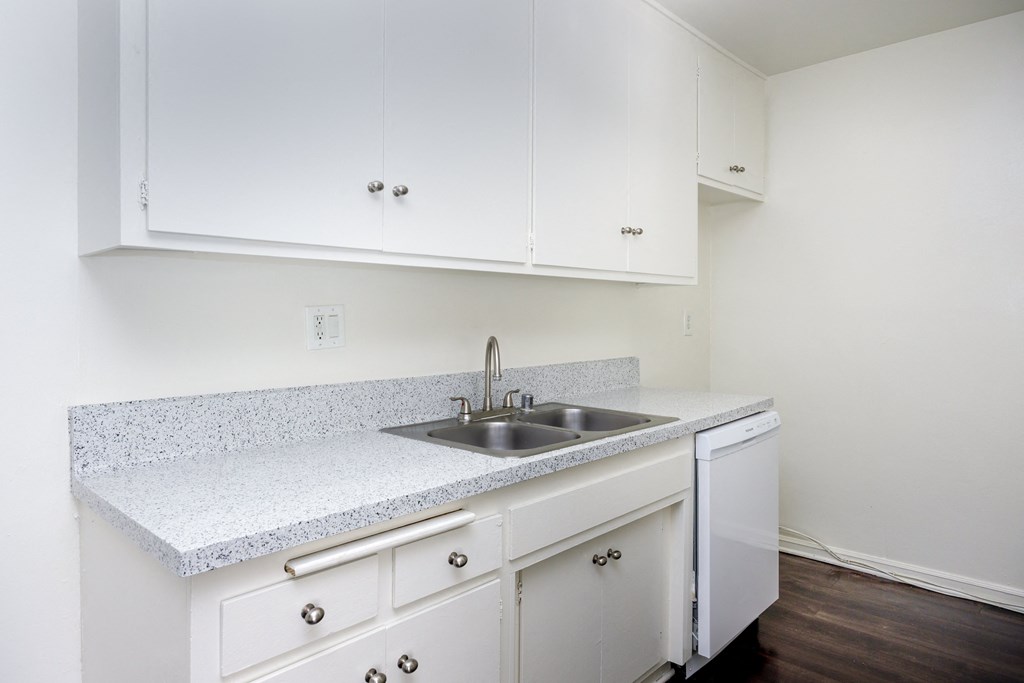 an empty kitchen with white cabinets and a sink