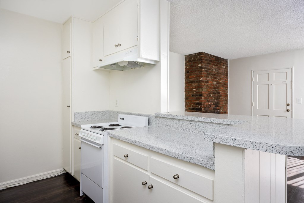 an empty kitchen with white appliances and granite counter tops