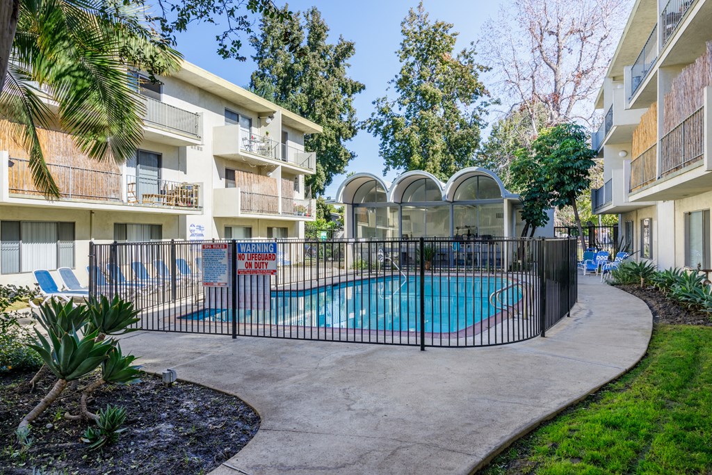 a swimming pool is behind a fence in front of an apartment building