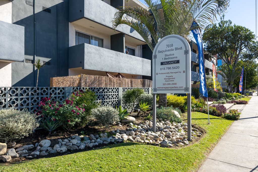 a sign in front of a building with palm trees