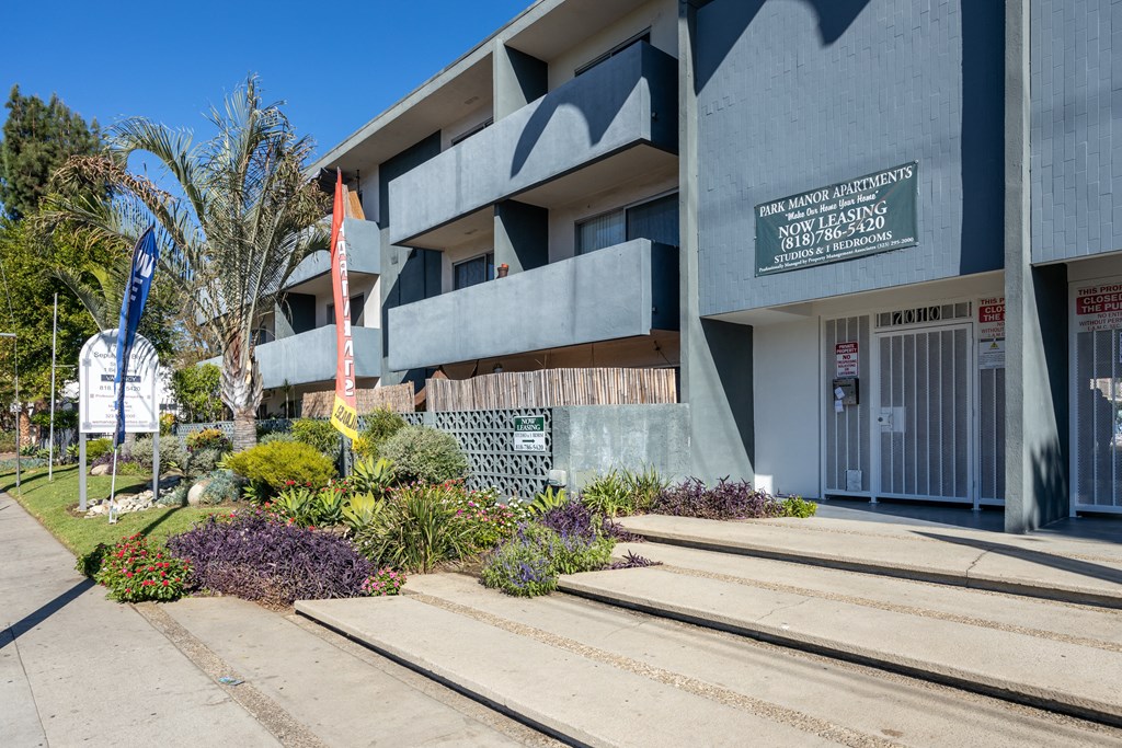 the front of a building with stairs and plants in front of it