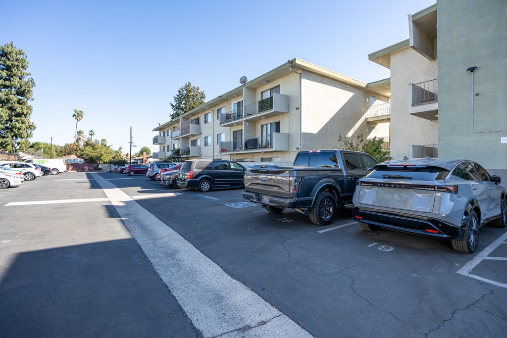 A parking lot with cars and apartment buildings in the background.
