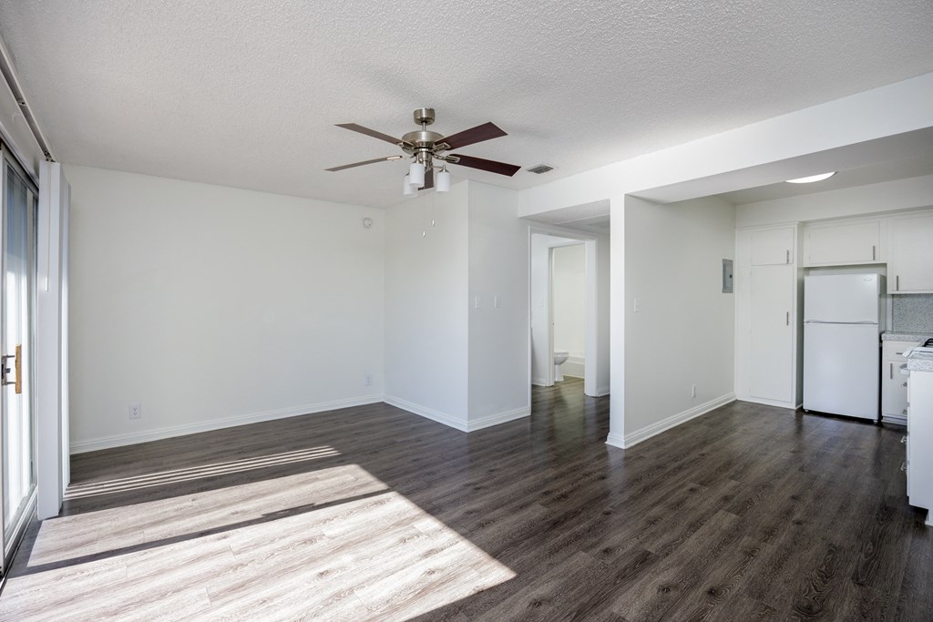 a living room with white walls and a ceiling fan