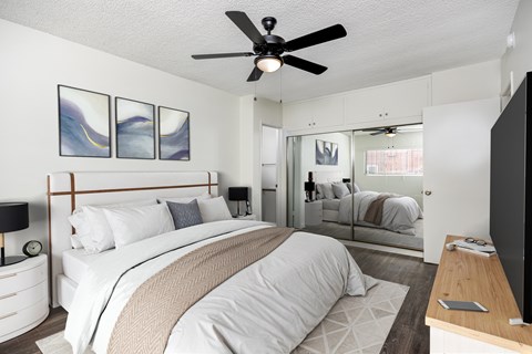 A bedroom with a large bed and a ceiling fan.
