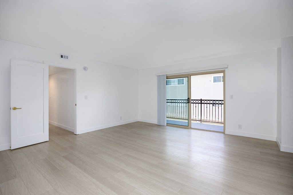 an empty living room with wood floors and a balcony