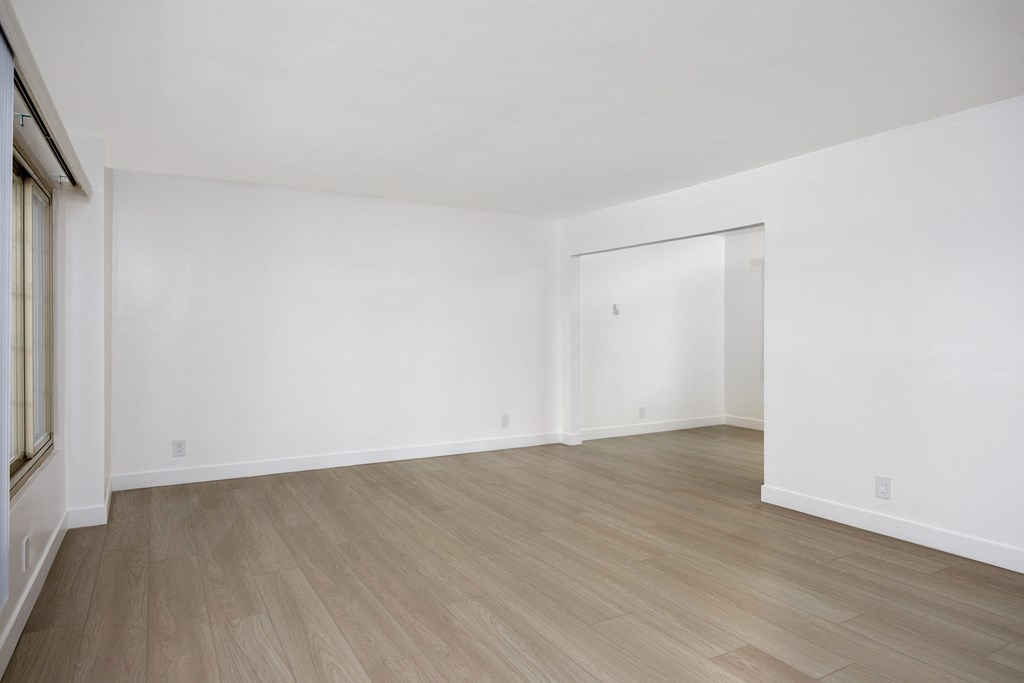 an empty living room with white walls and wood flooring