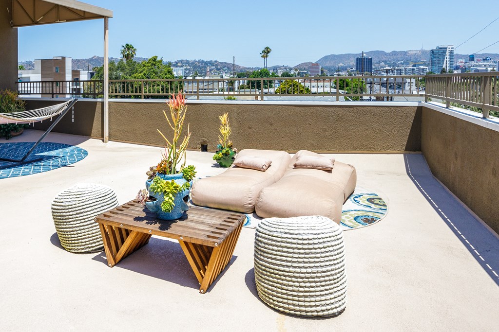 a rooftop terrace with couches and tables and a view of the city