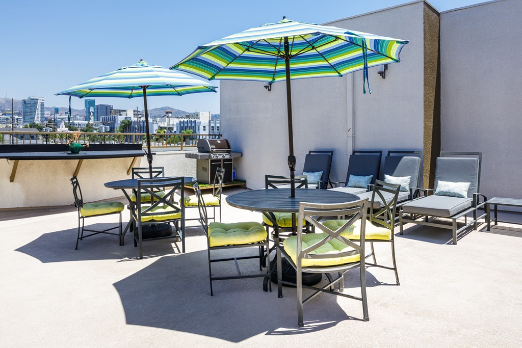 a patio with tables and chairs and umbrellas on the roof of a building