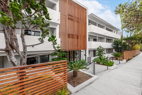 A modern building with a wooden fence and plants in front.