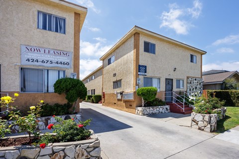 A street view of a Now Leasing sign in front of a building.