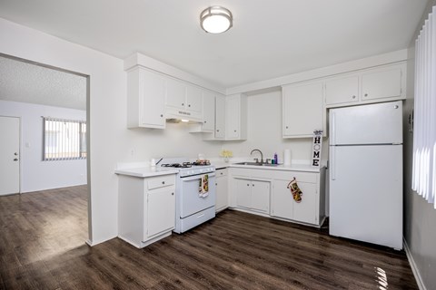 A kitchen with white cabinets and a wooden floor.