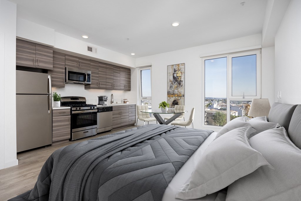 a bedroom with a bed and a kitchen with stainless steel appliances