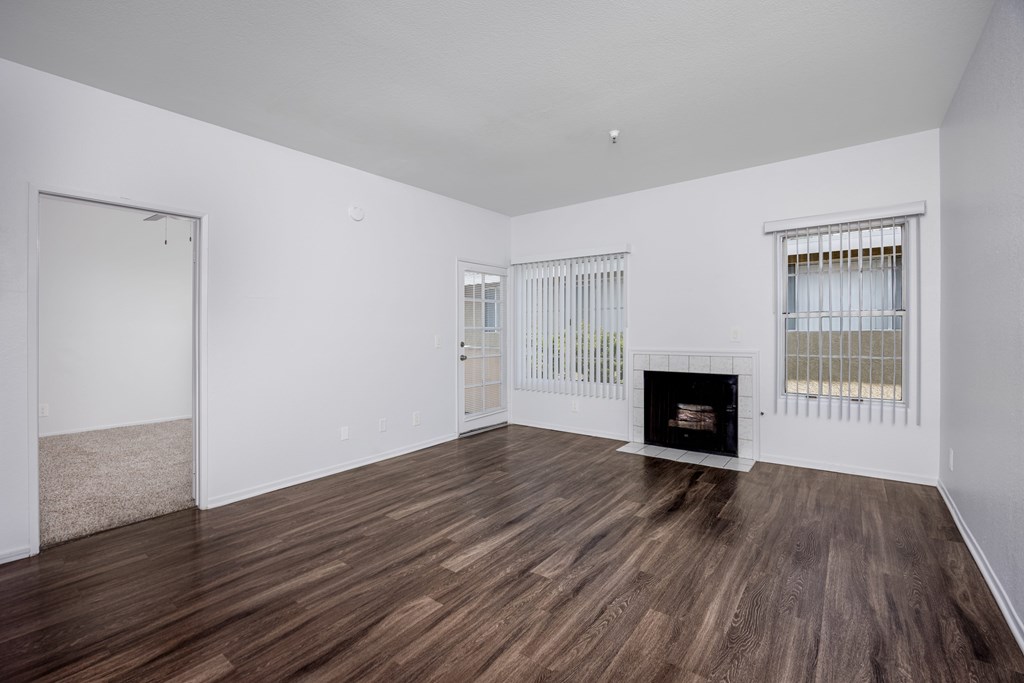 A room with a fireplace and wood flooring.