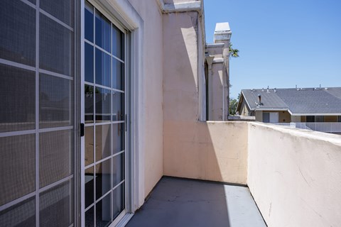 A balcony with a closed glass door and a white railing.