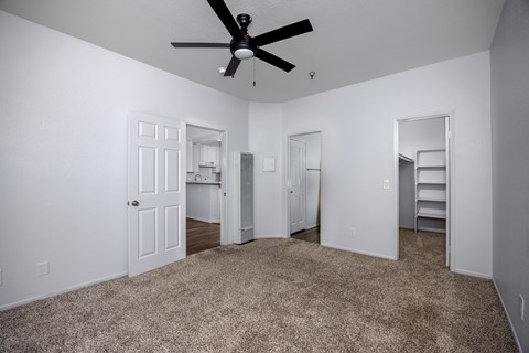 A room with a ceiling fan and carpeted floor.