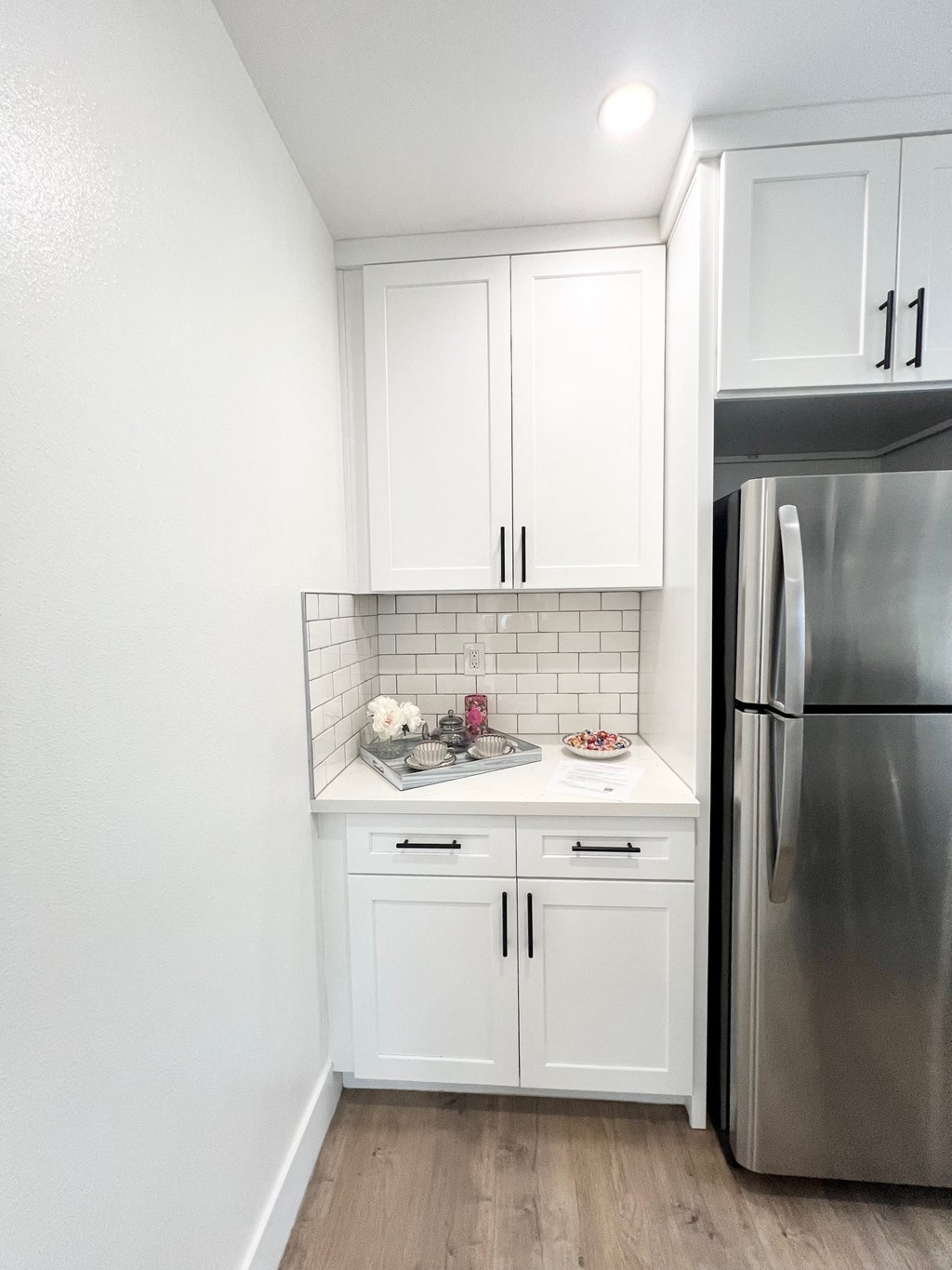 a kitchen with white cabinets and a stainless steel refrigerator