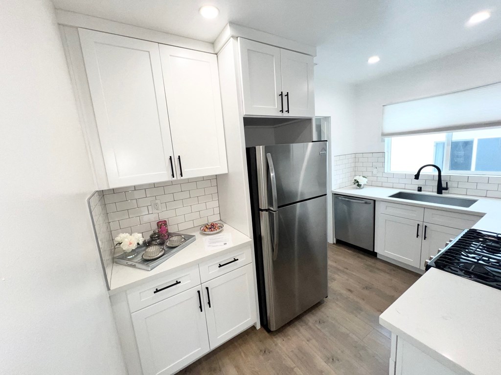 a kitchen with white cabinets and a stainless steel refrigerator