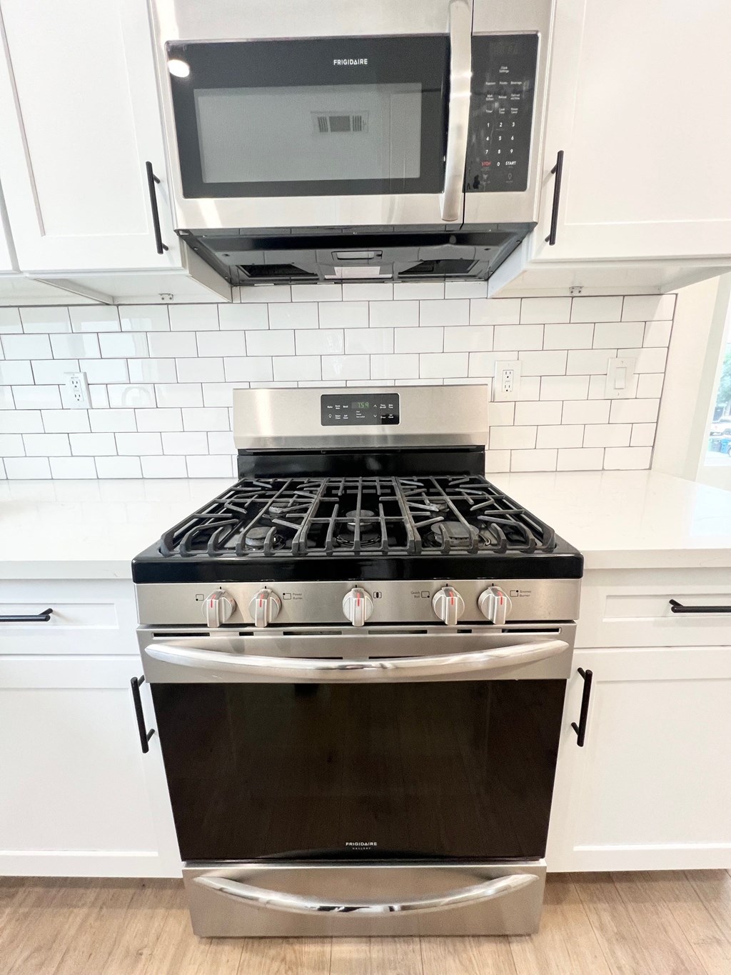 a white kitchen with a stove and a microwave