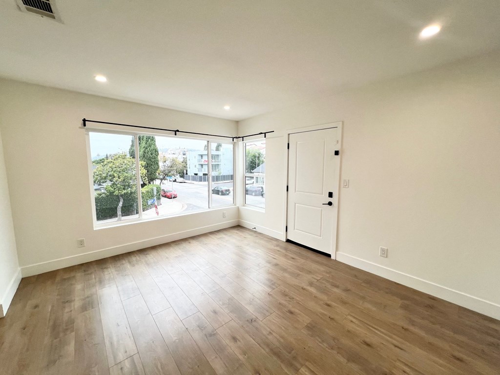 an empty living room with a large window and wooden floors