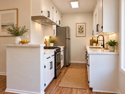 A white kitchen with a refrigerator, stove, and sink.