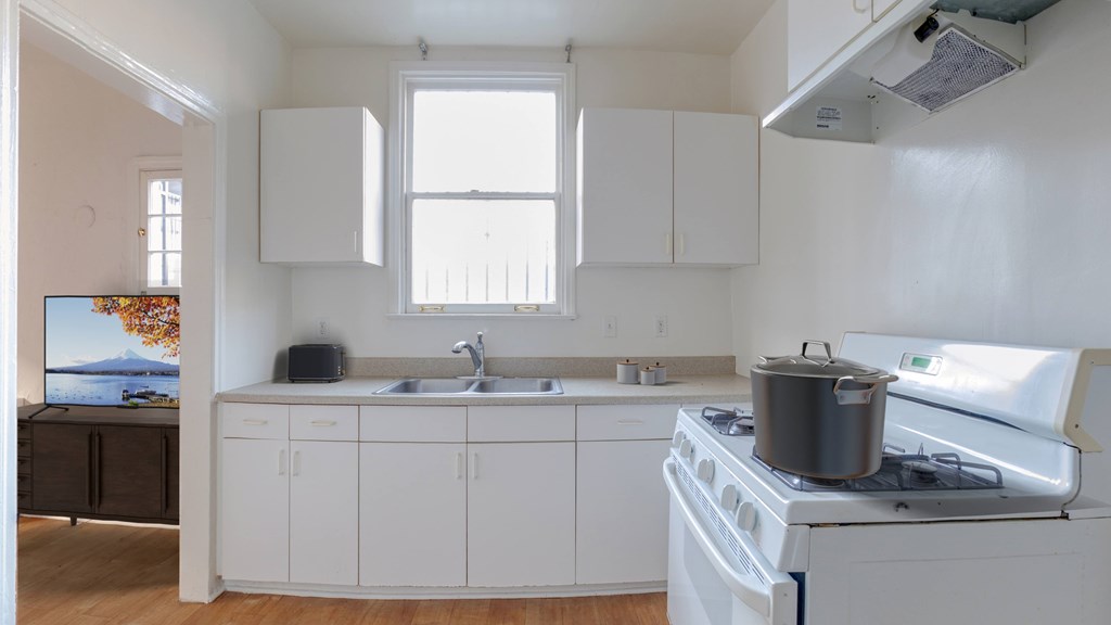 A kitchen with white cabinets and a stove top oven.