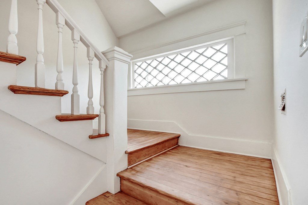a landing with wooden stairs and a window on the top of the stairs