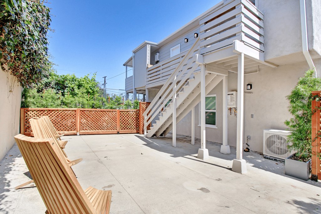 the patio of a house with stairs and a wooden bench