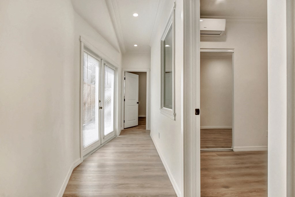 a hallway with white walls and white doors and wood floors
