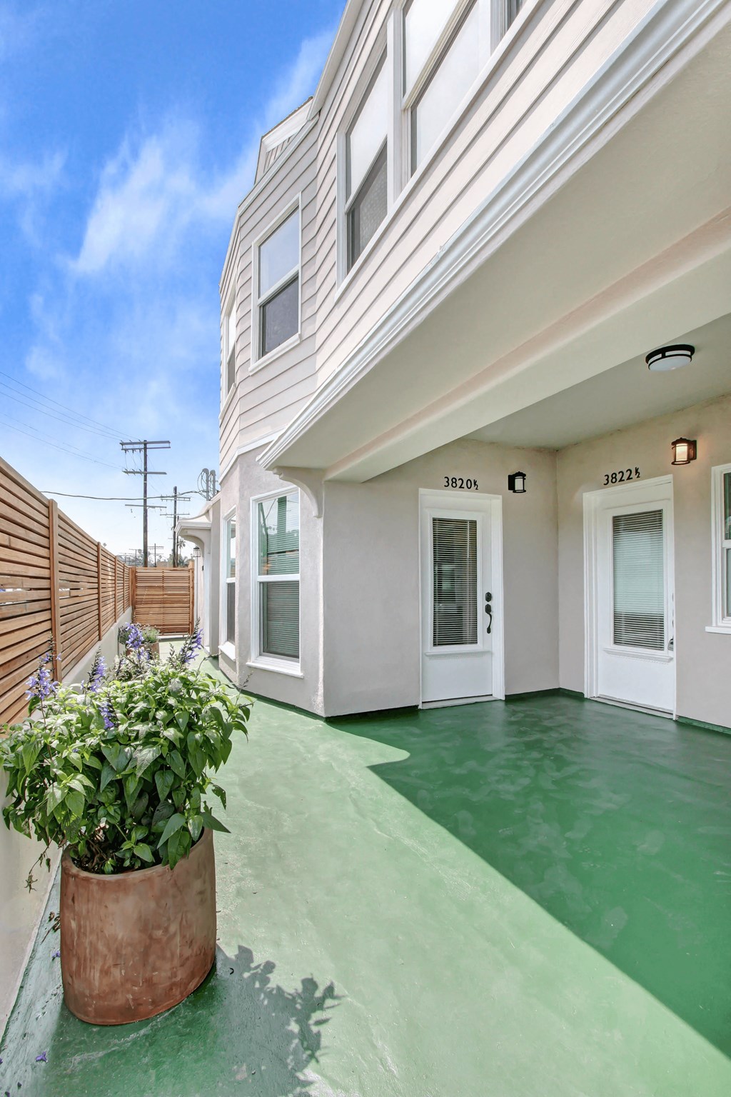 the front entrance of a white house with a green sidewalk and a potted plant