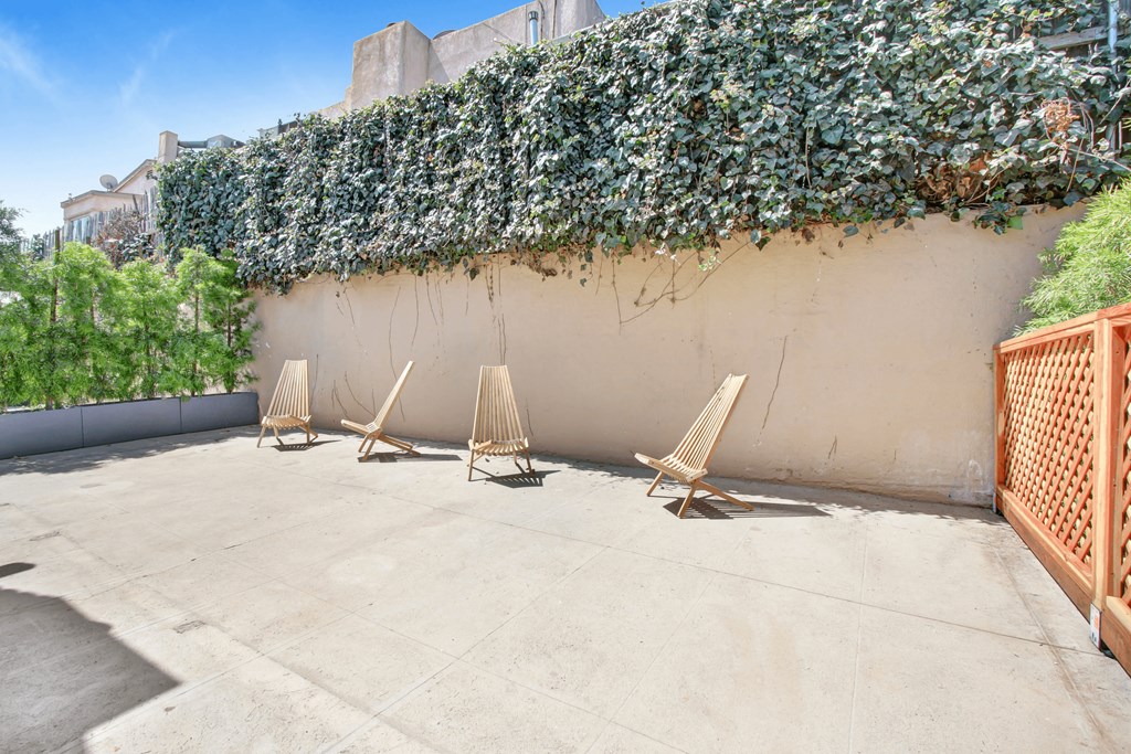 a patio with chairs and a wall with a ivy plant