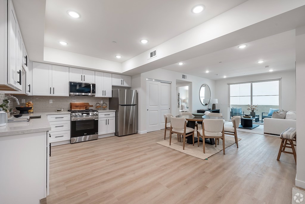 A modern kitchen with wooden floors and white cabinetry.