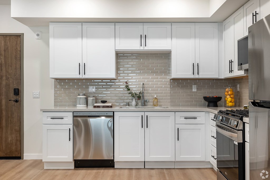A kitchen with white cabinets and a brick backsplash.