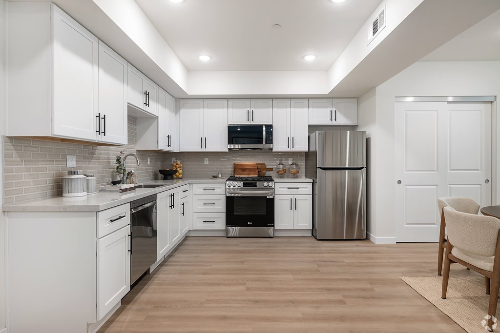 A modern kitchen with white cabinets and stainless steel appliances.