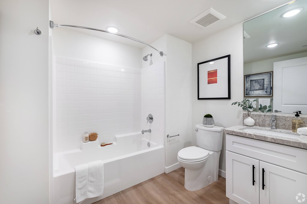 A white bathroom with a towel hanging on the tub.