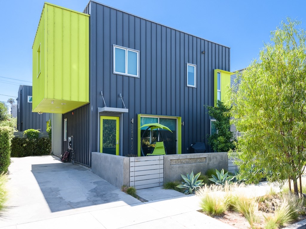 a black house with yellow doors and a sidewalk