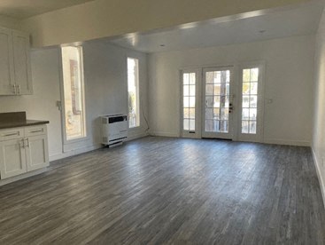 an empty living room with white walls and wood floors
