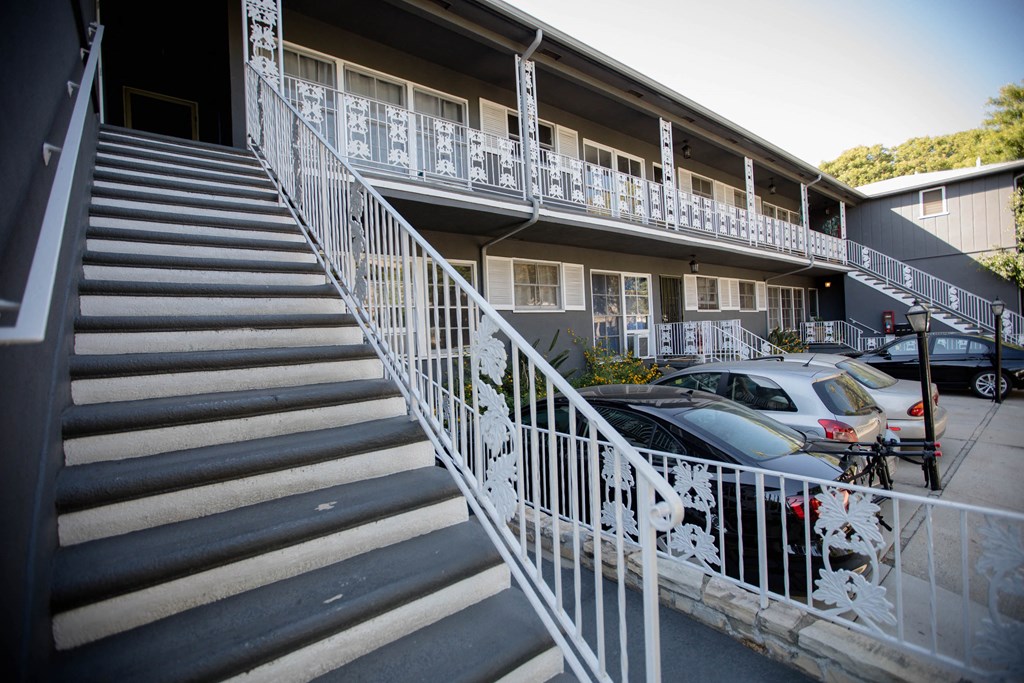 the side of an apartment building with stairs and a parking lot