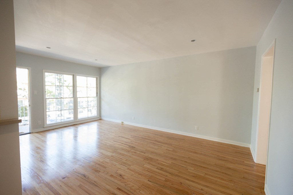 an empty living room with white walls and wood floors