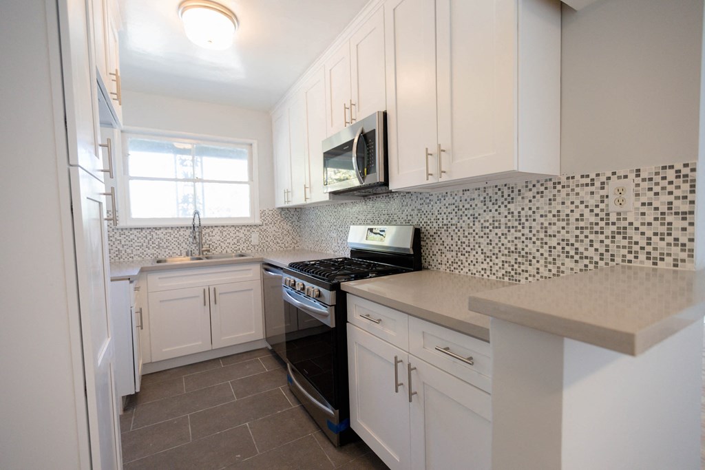 a kitchen with white cabinets and a stove and a microwave