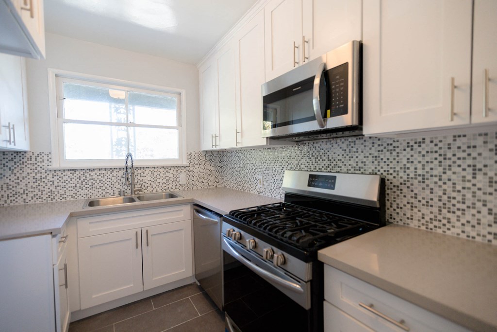 a kitchen with white cabinets and a stove and a microwave