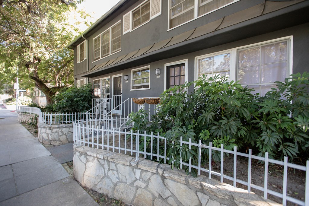 the exterior of a gray house with a white fence